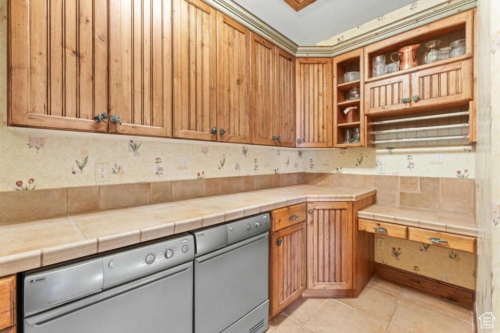 Kitchen with dishwasher, tile countertops, and light tile flooring