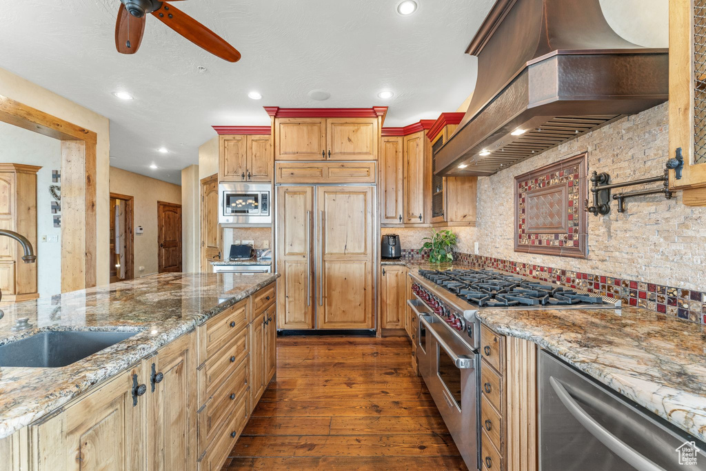 Kitchen featuring tasteful backsplash, dark hardwood / wood-style floors, built in appliances, custom range hood, and ceiling fan