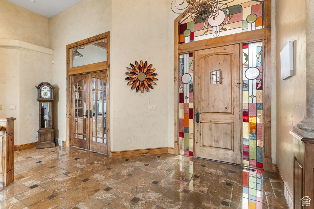 Entryway featuring a notable chandelier, a high ceiling, and dark tile flooring