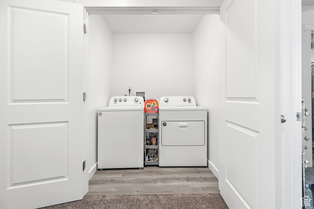 Laundry room with light hardwood / wood-style floors, washing machine and dryer, and hookup for a washing machine