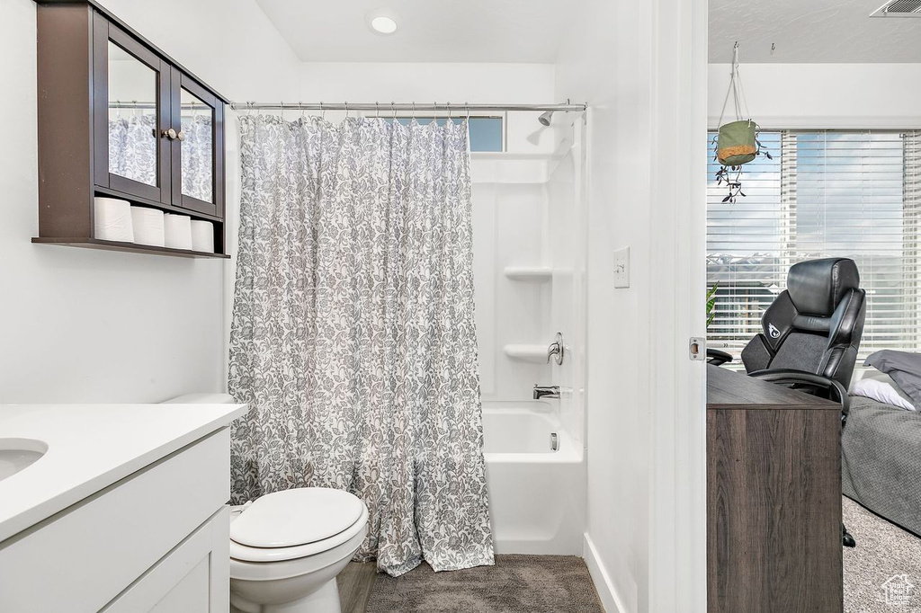 Full bathroom with a healthy amount of sunlight, toilet, vanity, and shower / tub combo