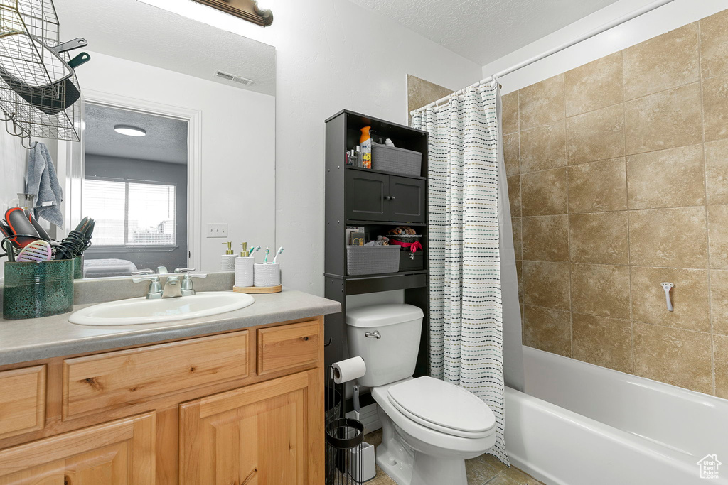 Full bathroom with shower / bathtub combination with curtain, tile floors, a textured ceiling, toilet, and vanity