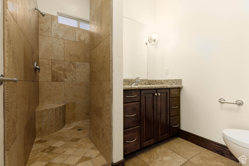 Bathroom featuring vanity, tile floors, toilet, and tiled shower