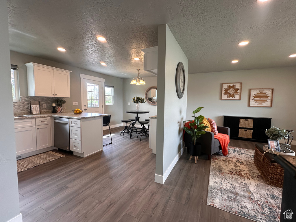 Kitchen with dark hardwood / wood-style floors, decorative light fixtures, white cabinets, and dishwasher
