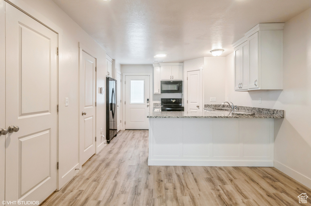 Kitchen with light hardwood / wood-style flooring, white cabinets, stainless steel refrigerator with ice dispenser, and range