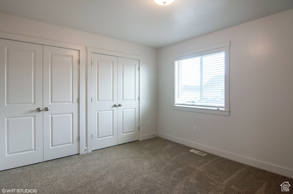 Unfurnished bedroom with dark colored carpet and multiple closets