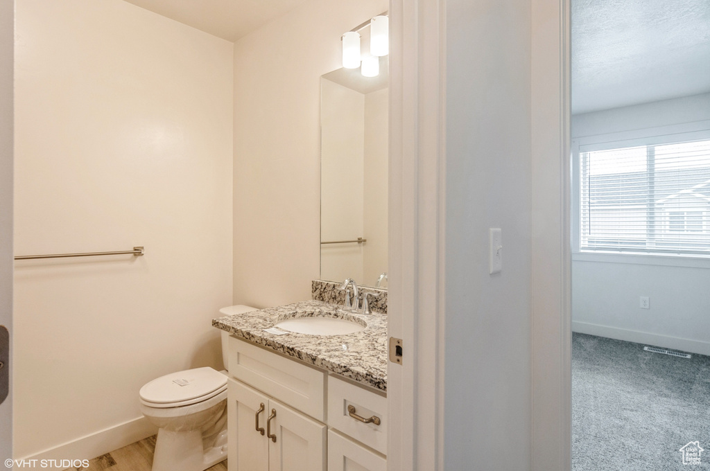 Bathroom featuring vanity with extensive cabinet space and toilet