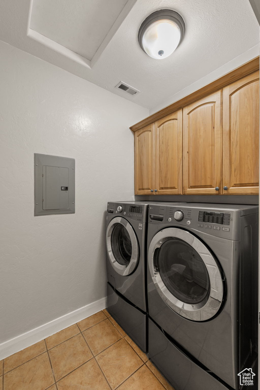Washroom featuring independent washer and dryer, light tile floors, and cabinets