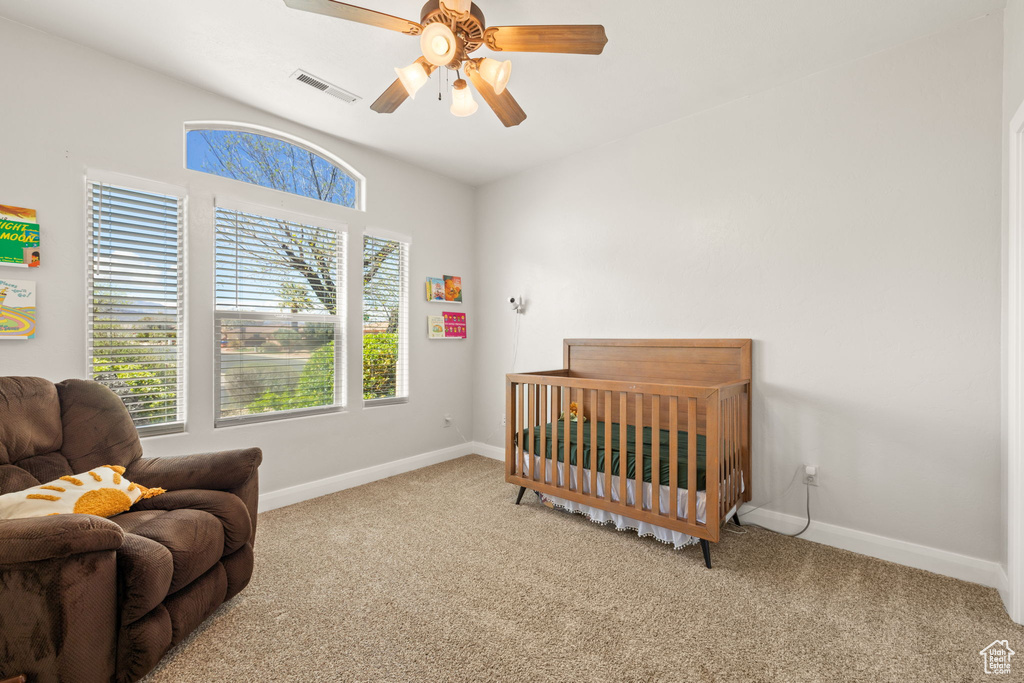 Carpeted bedroom with ceiling fan and a nursery area