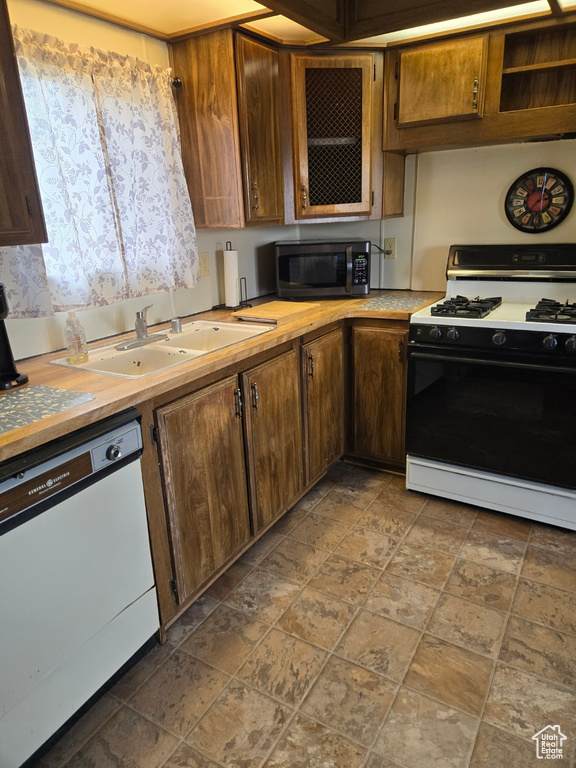 Kitchen featuring dark tile floors, white appliances, and sink
