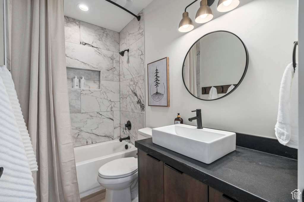Full bathroom featuring vanity with extensive cabinet space, shower / tub combo, and toilet