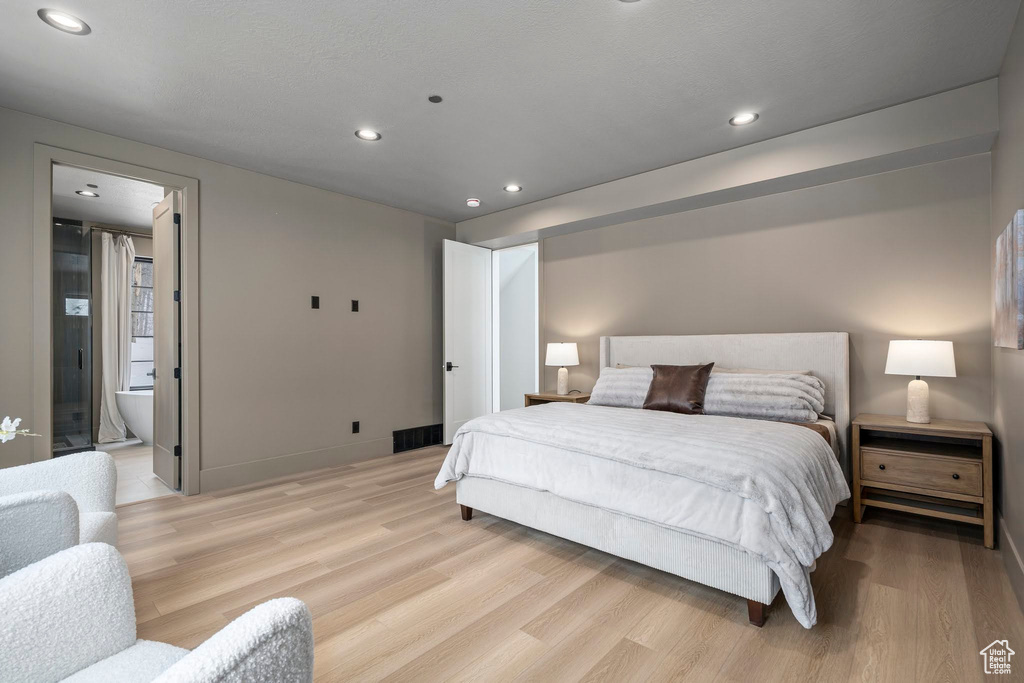 Bedroom with connected bathroom and light hardwood / wood-style flooring