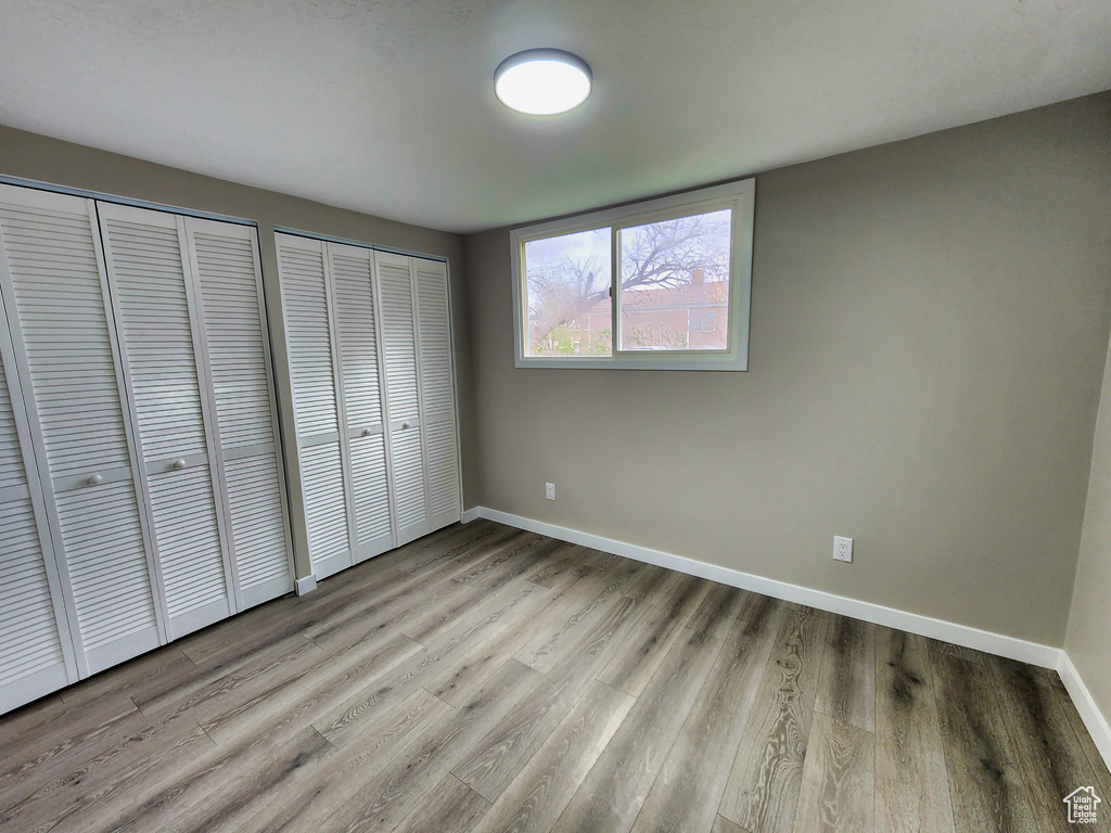 Unfurnished bedroom featuring multiple closets and light hardwood / wood-style flooring