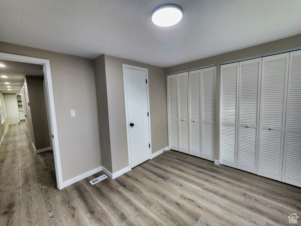 Unfurnished bedroom featuring multiple closets and light wood-type flooring