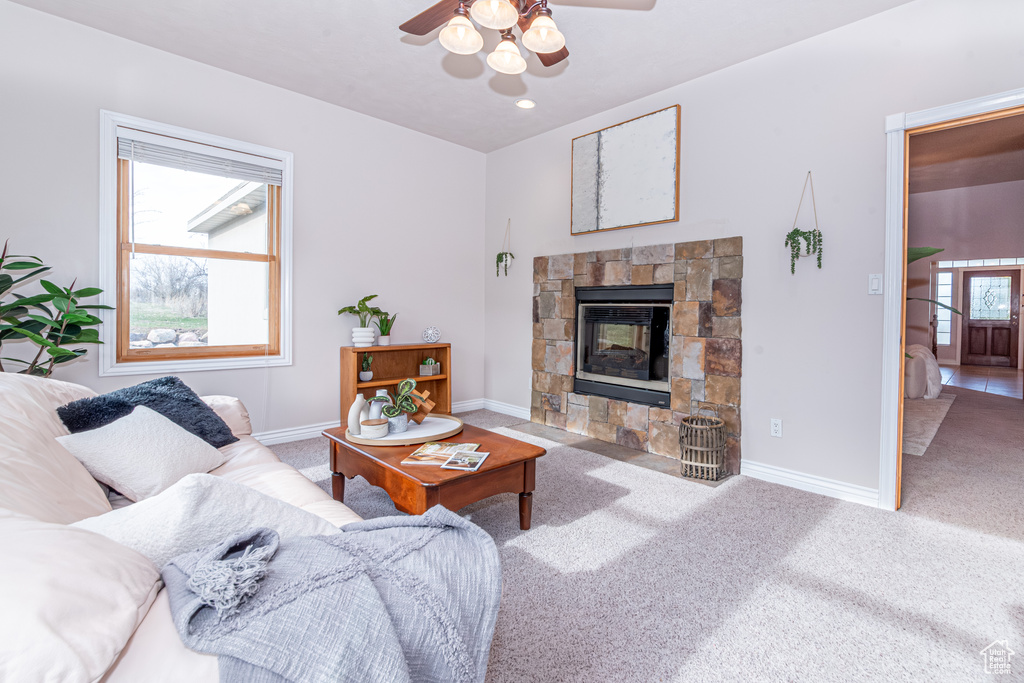 Living room featuring light carpet, ceiling fan, and a fireplace