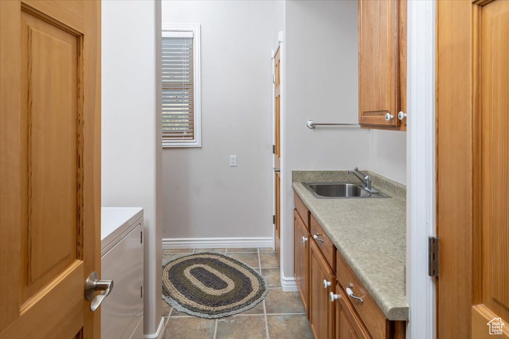 Washroom with cabinets, light tile flooring, sink, and washer / dryer
