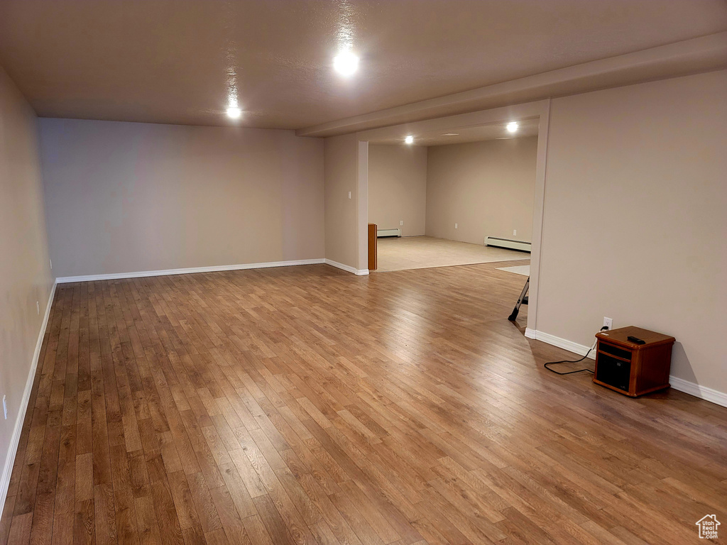 Basement with light wood-type flooring and a baseboard heating unit