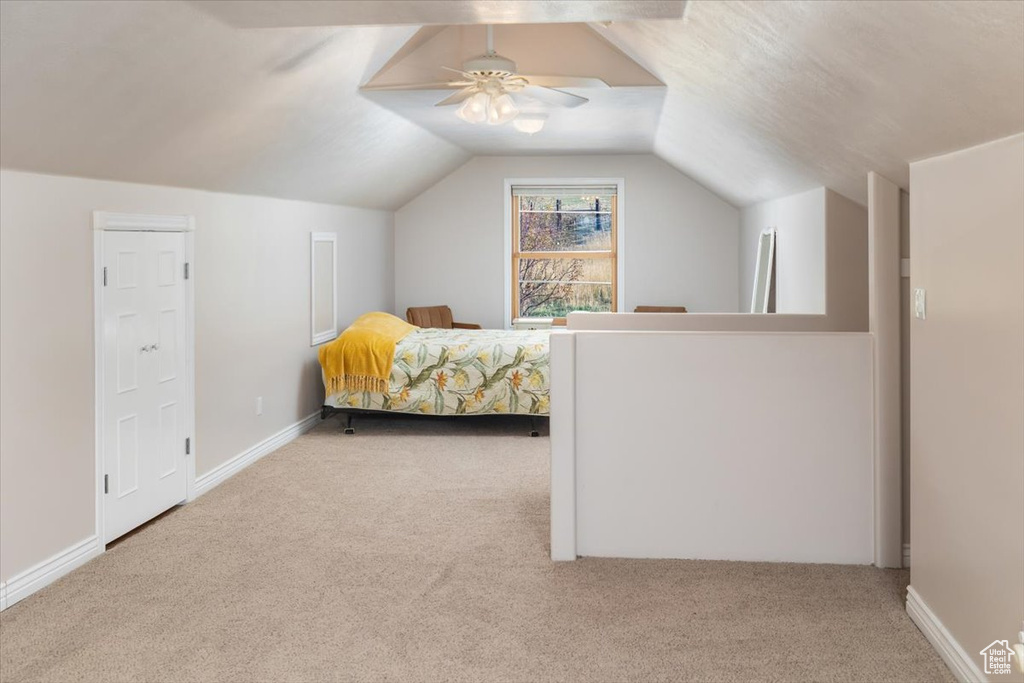 Bedroom with lofted ceiling, ceiling fan, and light carpet