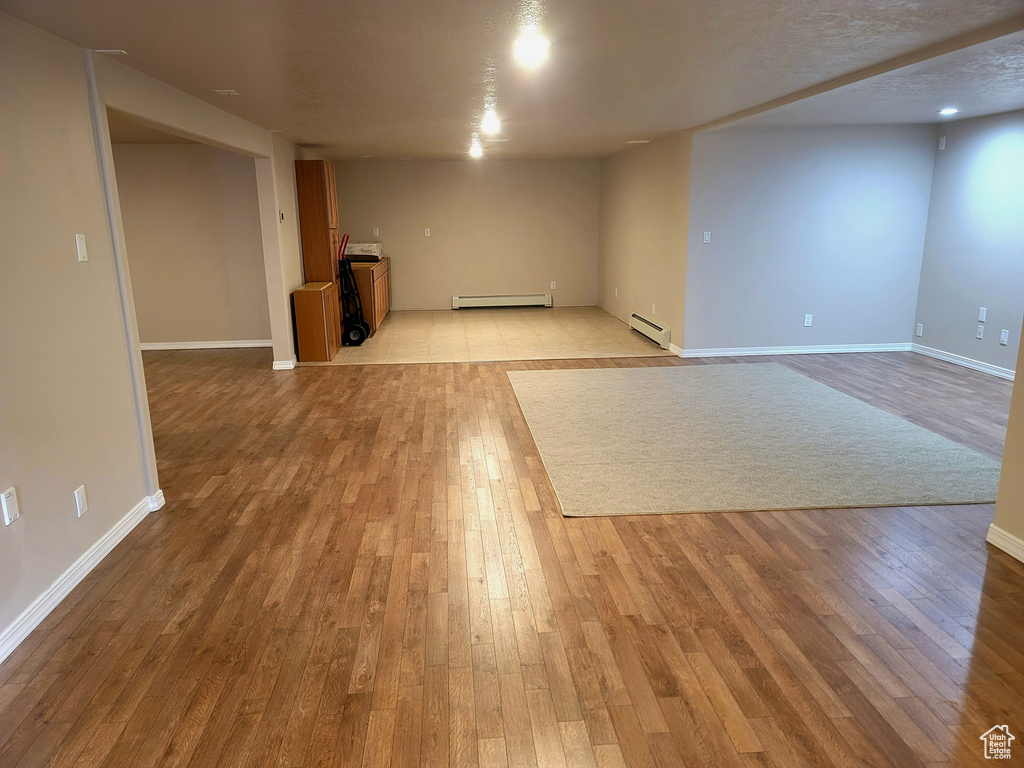 Basement with light tile flooring and a baseboard heating unit