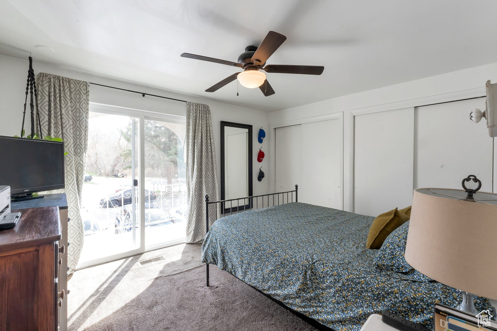 Bedroom with multiple closets, ceiling fan, carpet flooring, and access to outside