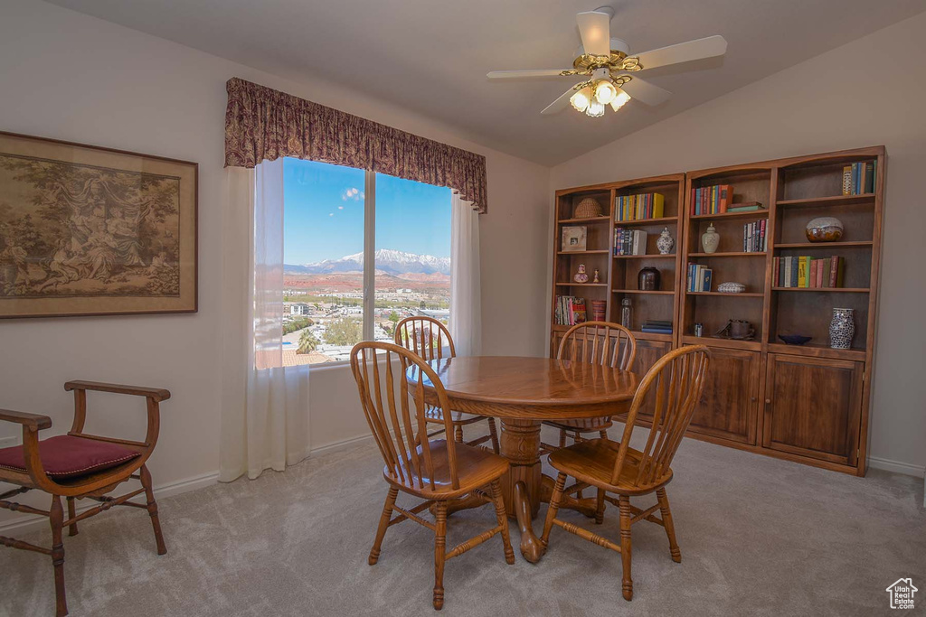 Dining room featuring ceiling fan, light carpet, and vaulted ceiling