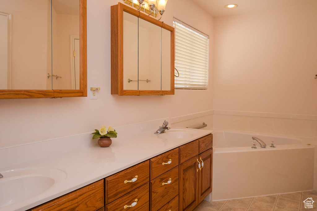 Bathroom featuring tile flooring, double sink, vanity with extensive cabinet space, and a bathtub