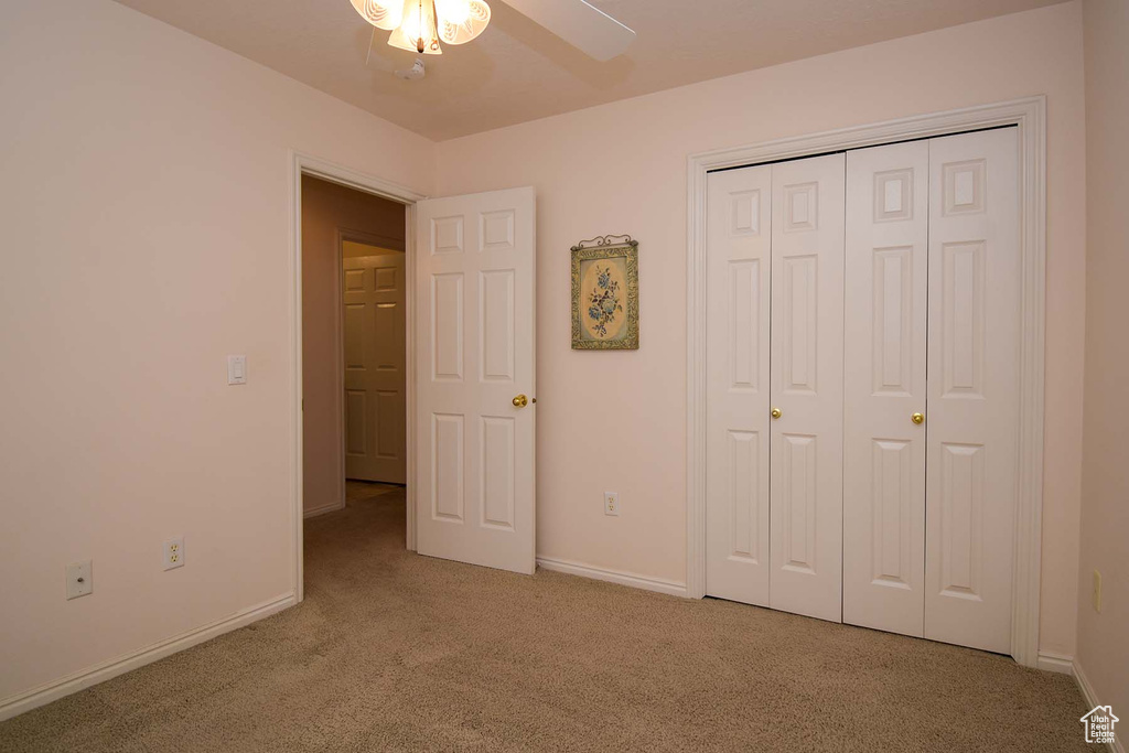 Unfurnished bedroom with ceiling fan, a closet, and light carpet