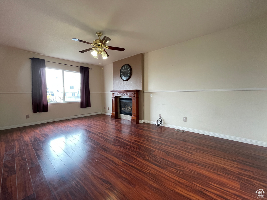Unfurnished living room featuring dark hardwood / wood-style floors and ceiling fan