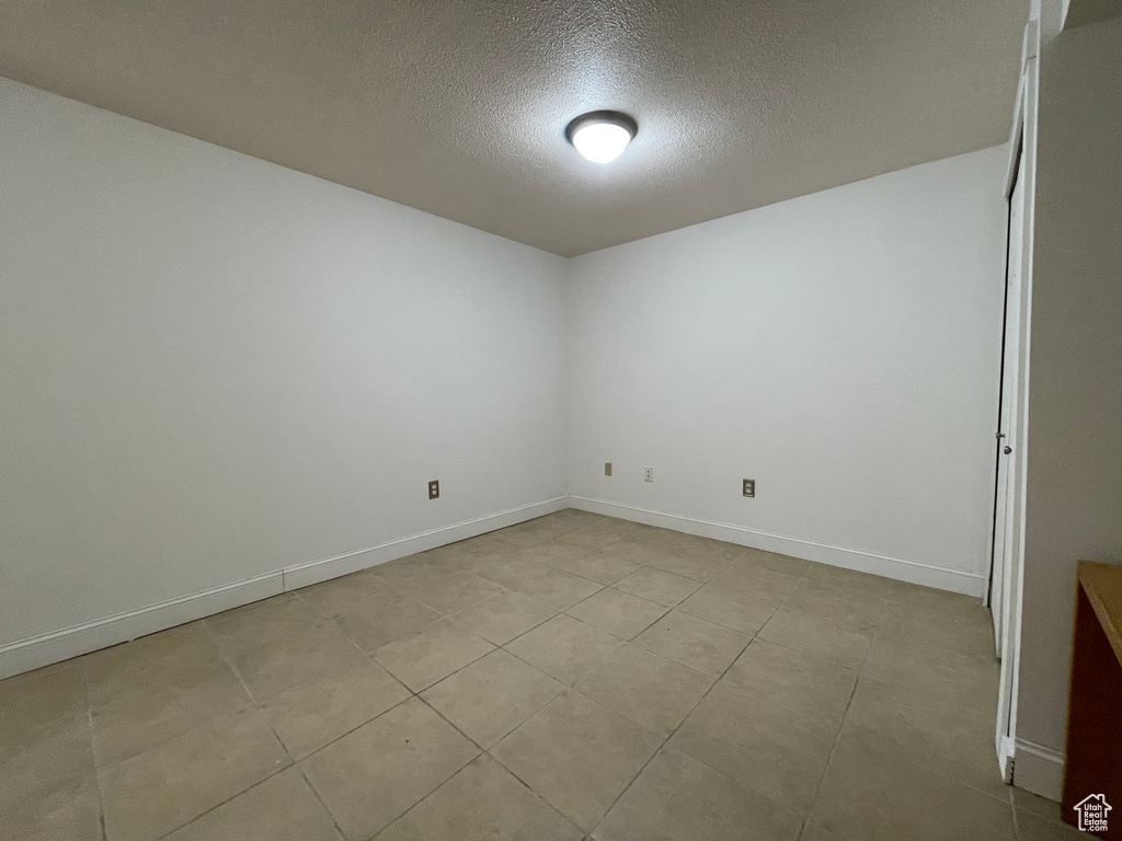 Empty room with a textured ceiling and light tile floors