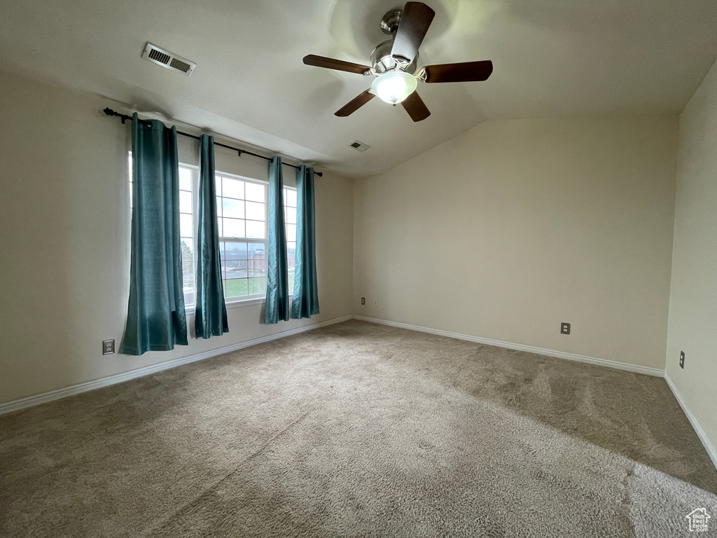 Unfurnished room with ceiling fan, light carpet, and vaulted ceiling