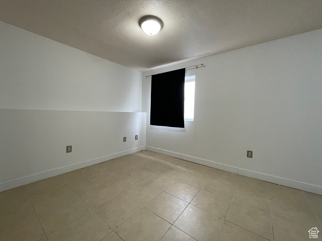 Tiled empty room featuring a textured ceiling