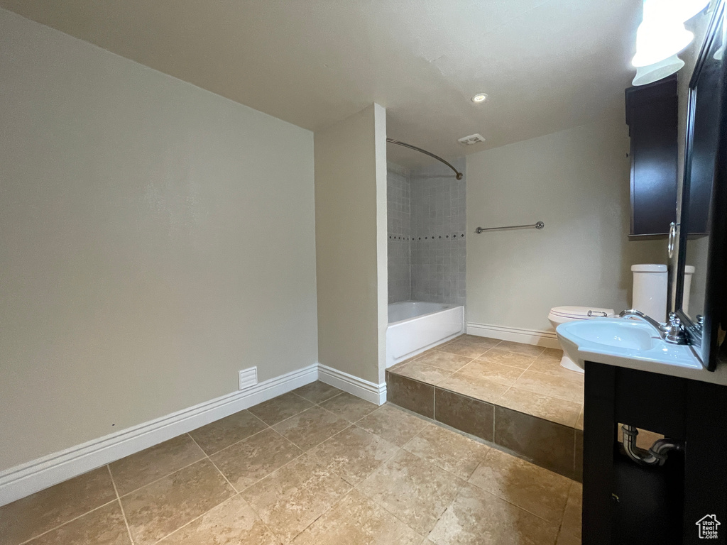 Full bathroom with tile flooring, toilet, vanity, and tiled shower / bath