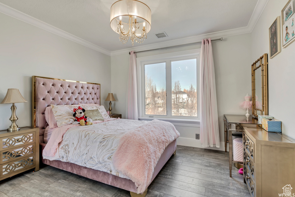 Bedroom with crown molding, hardwood / wood-style floors, a chandelier, and multiple windows