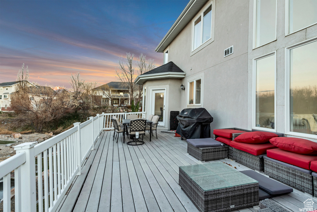 Deck at dusk featuring a grill and outdoor lounge area