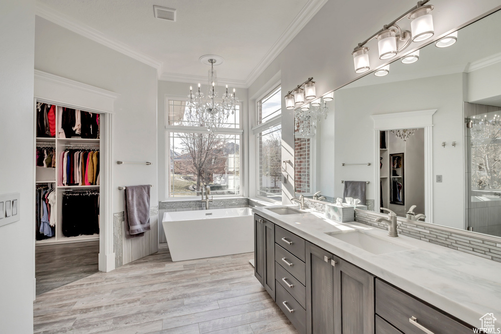 Bathroom with hardwood / wood-style flooring, a chandelier, oversized vanity, and dual sinks
