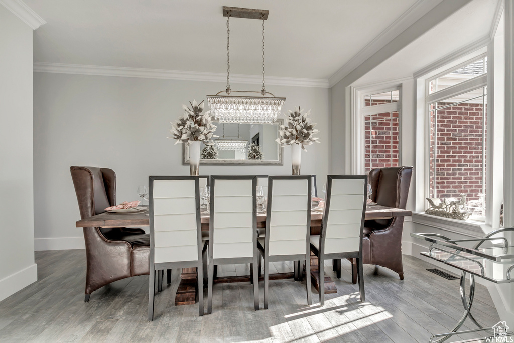 Dining room with ornamental molding, a notable chandelier, and light hardwood / wood-style flooring