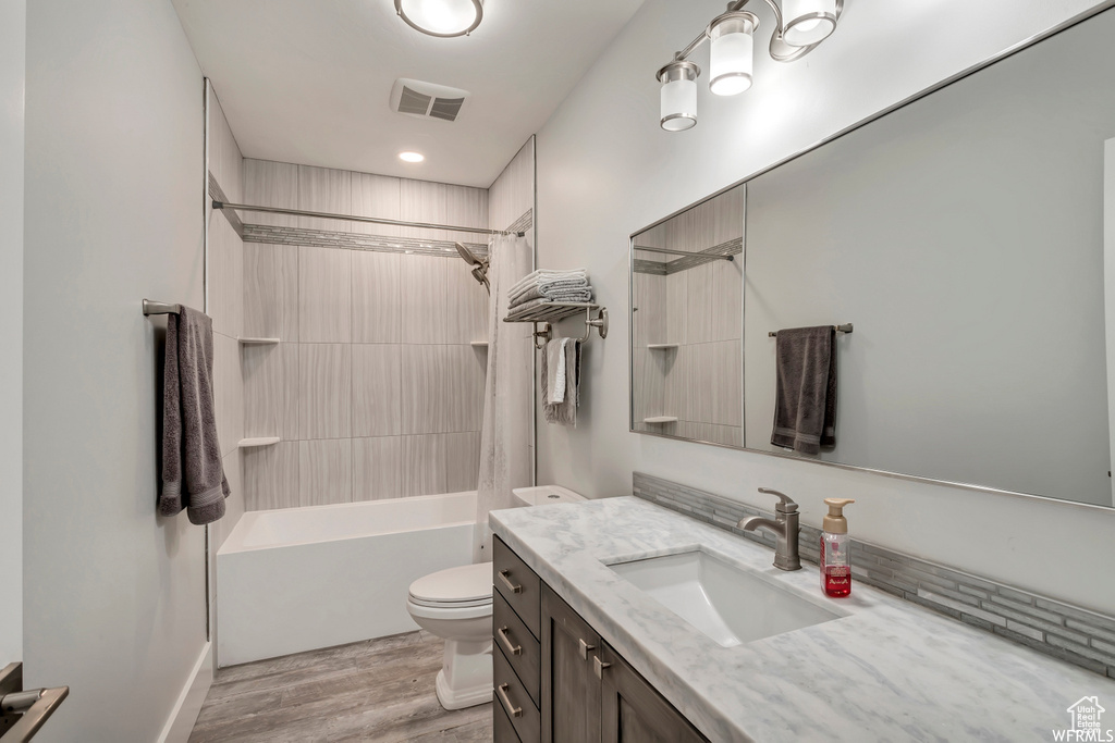 Full bathroom with oversized vanity, hardwood / wood-style floors, toilet, and washtub / shower combination