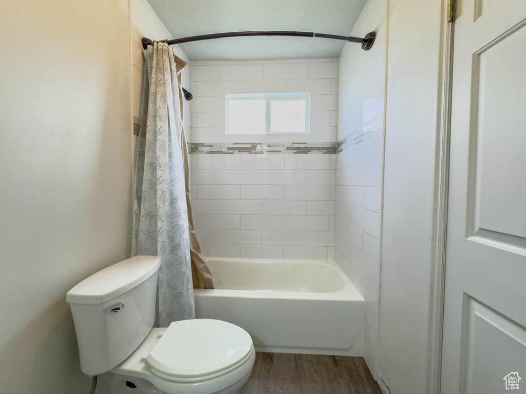 Bathroom featuring shower / bath combo, hardwood / wood-style floors, and toilet