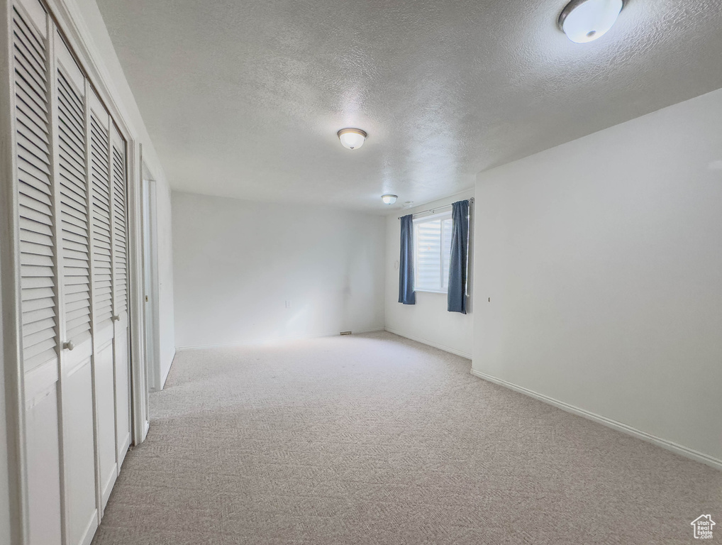Unfurnished bedroom with light colored carpet and a textured ceiling