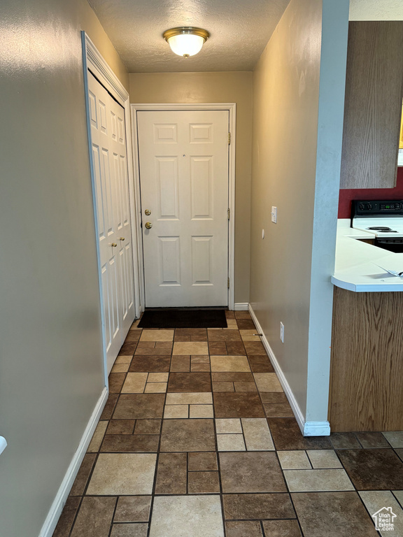 Doorway featuring dark tile floors and a textured ceiling