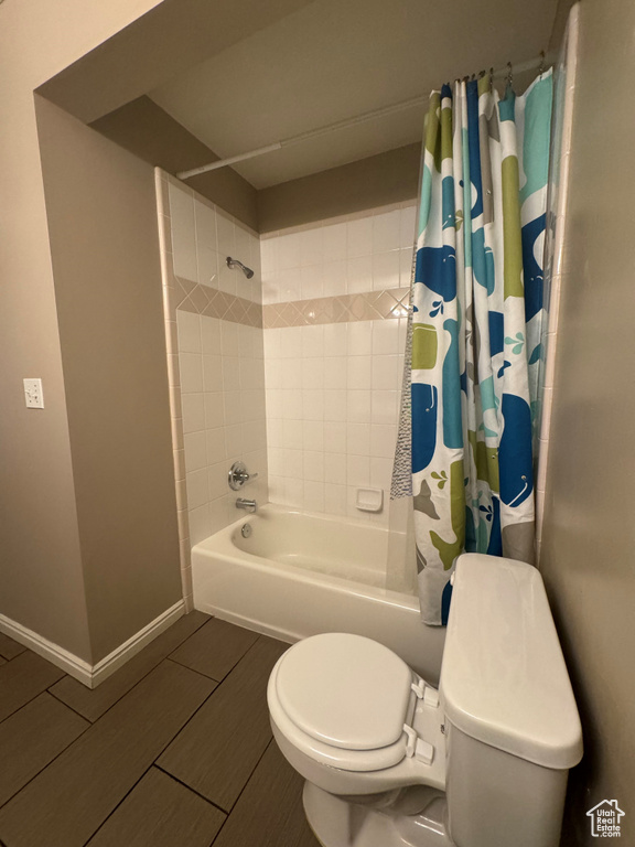 Bathroom with tile flooring, shower / bathtub combination with curtain, and toilet