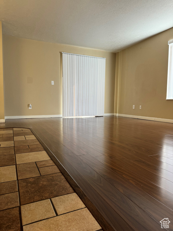 Empty room featuring a textured ceiling and dark hardwood / wood-style floors