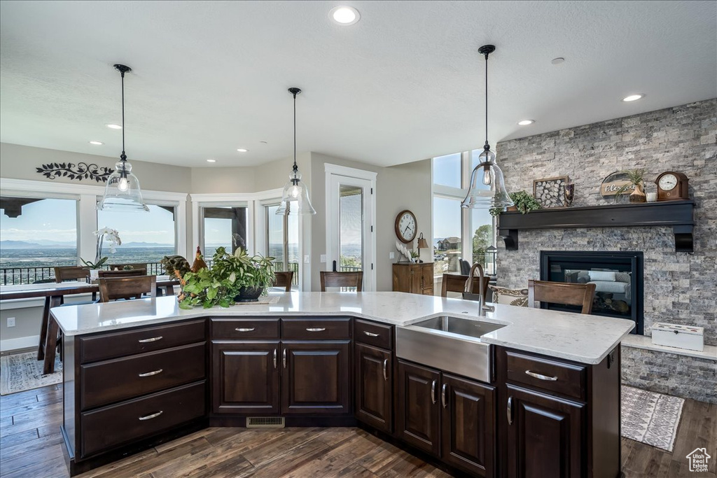 Kitchen featuring hanging light fixtures, dark brown cabinets, sink, and a stone fireplace