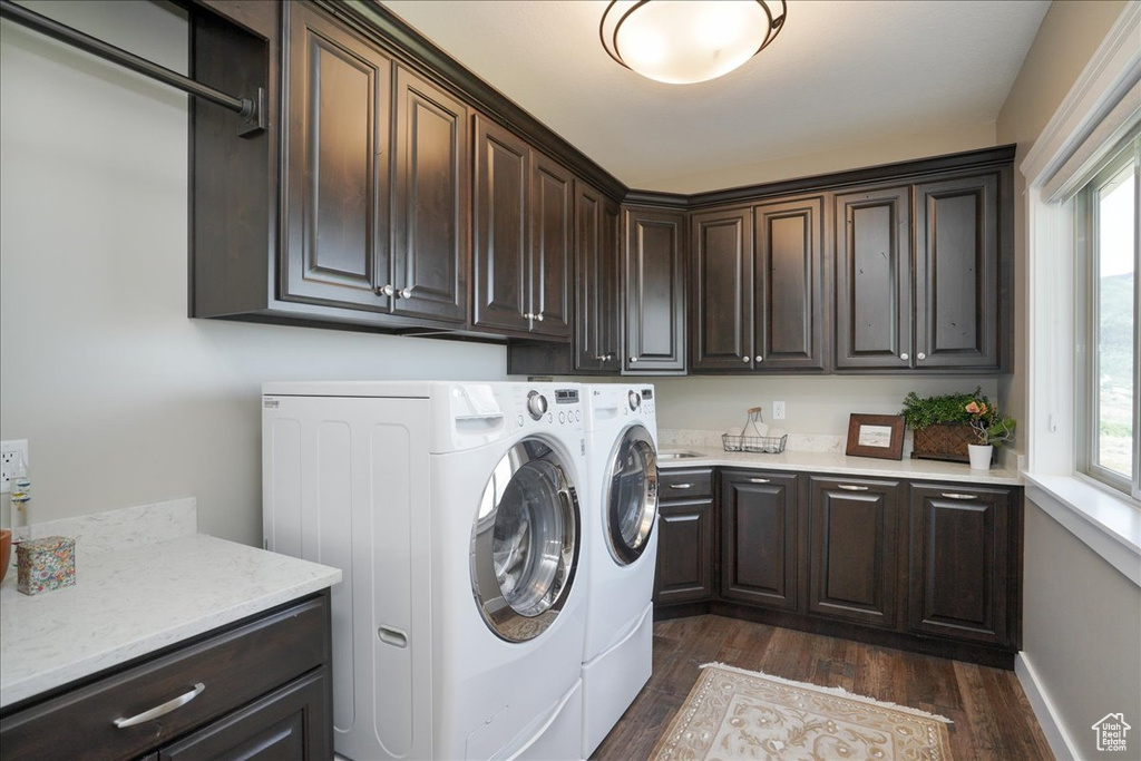 Laundry room featuring washer and clothes dryer, dark hardwood / wood-style flooring, cabinets, and a healthy amount of sunlight
