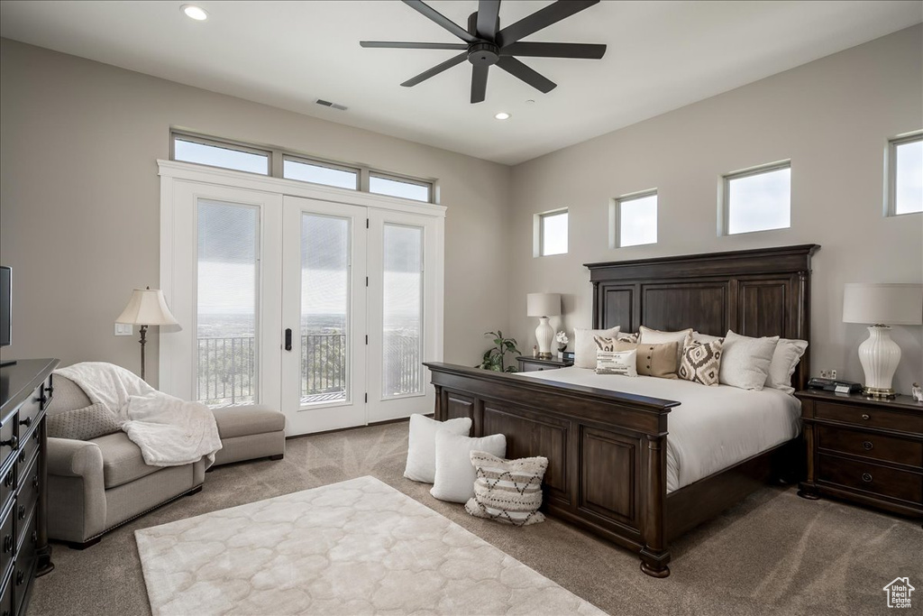 Bedroom featuring ceiling fan, access to exterior, light carpet, and multiple windows