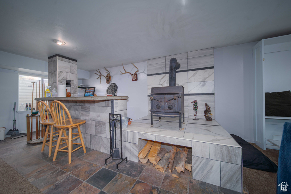 Interior space featuring tile walls, a wood stove, and dark tile flooring