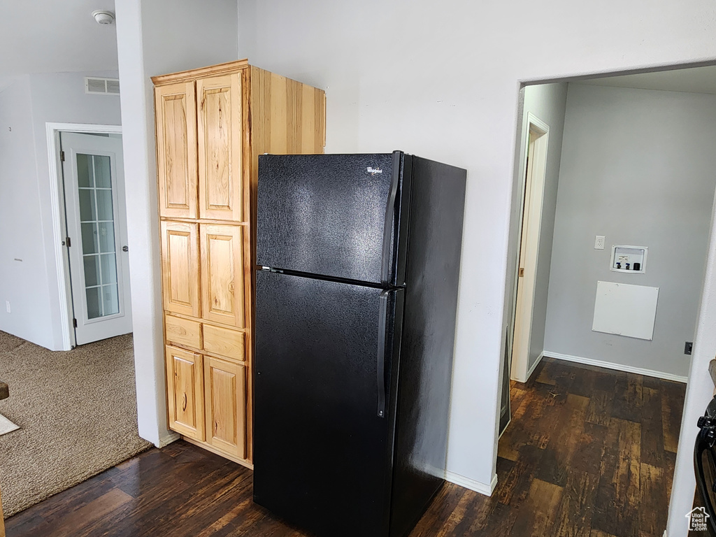 Kitchen featuring light brown cabinets, dark wood-type flooring, and black fridge