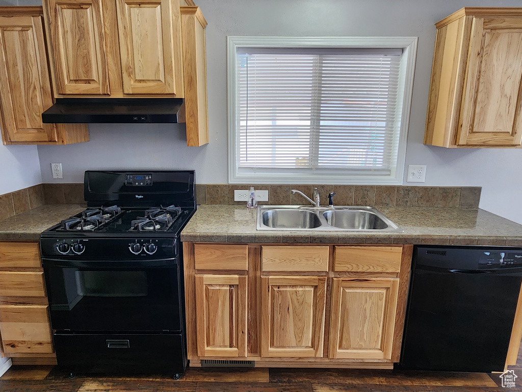 Kitchen with dark hardwood / wood-style flooring, sink, and black appliances