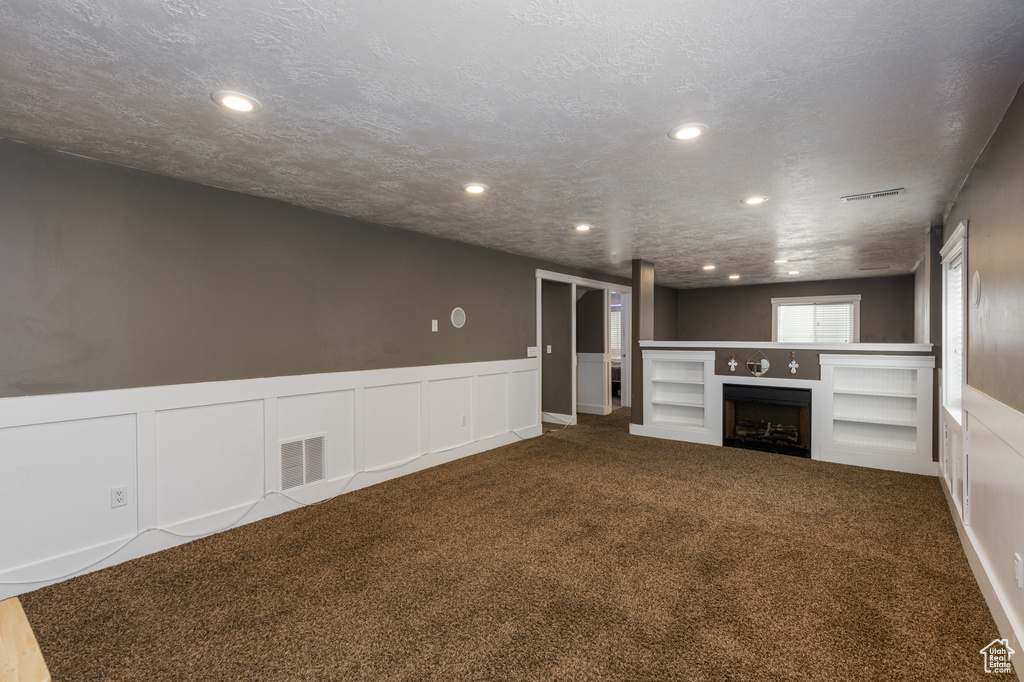 Unfurnished living room with carpet floors and a textured ceiling