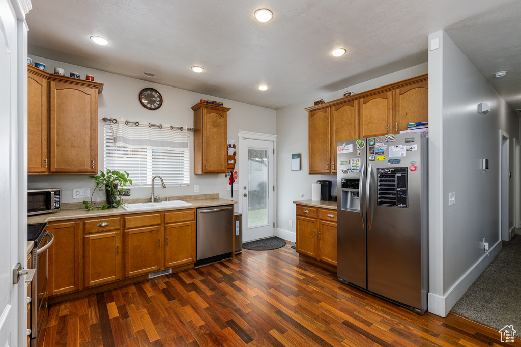 Kitchen with appliances with stainless steel finishes, dark colored carpet, and sink